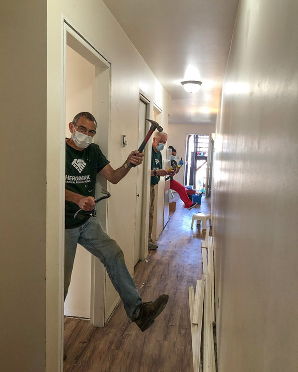 Volunteers show off their tools at a HeroWork renovation site. The charity, which renovates other charities, organizes its renovations around community events that often include meals and music.