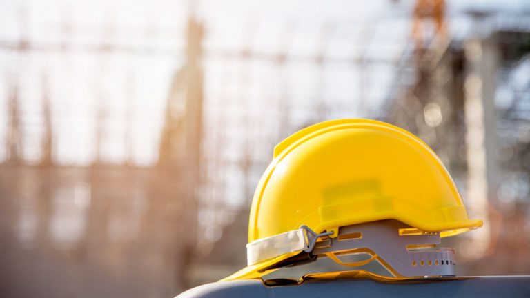A hard hat rests in front of a construction site.