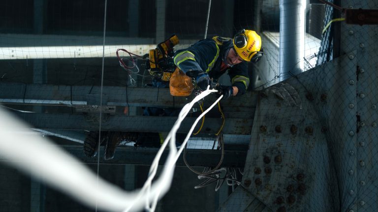 A Tatras worker installs netting underneath a bridge. The company provides netting to prevent bird nesting and debris from falling
