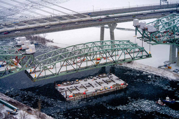 The Champlain Bridge deconstruction work on the water is being carried out by two methods: the use of a dozen barges, and the build-out of jetties where the river is too shallow for the barges. The barges themselves move around and are configurated like jigsaw puzzles around the remaining bridge piers after the bridge deck spans have been removed.