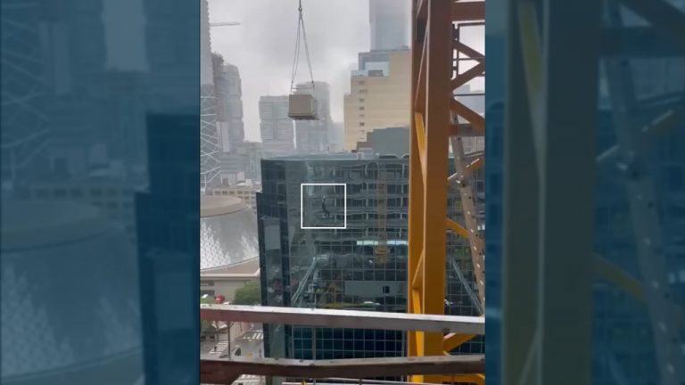 Social media video posted on Tuesday, July 5 shows a worker dangling from a construction crane load at the corner of Front Street West and Simcoe Street in Toronto. The worker was onsite for a PCL Constructors Canada project.