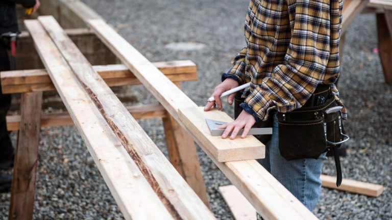 A carpenter makes a measurement. Lumber is just one of the many materials that have fluctuated wildly in price in recent years.