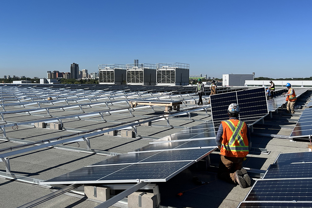 Workers attend to panels on the solar array on the Edmonton Expo Centre roof. The array is the largest rooftop array in Canada.
