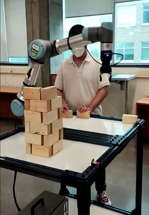 Robotic arm building a brick tower.
