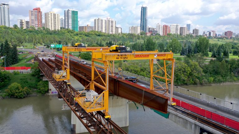 Gantry cranes mounted on steel beams and trusses over the North Saskatchewan River carry away pieces of the Groat Road bridge, some weighing nearly 80 tonnes.