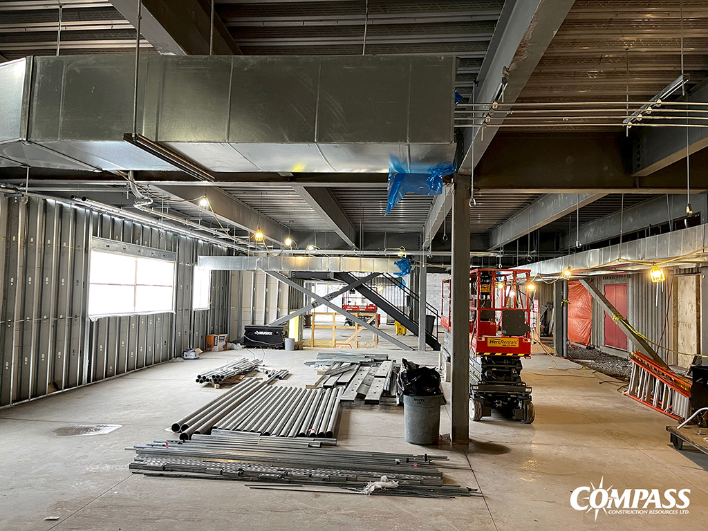 COURTESY COMPASS CONSTRUCTION — For the interior of the building, ongoing mechanical and electrical works are taking place with new HVAC duct work and conduit runs. Also pictured are exterior stud walls; new openings for windows and doors; structural cross bracing; temporary power and lighting; and safety railings.