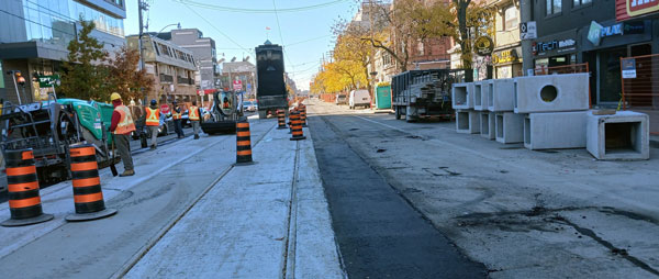 Pictured are crews paving asphalt and cleaning up completed tracks on College Street near Spadina Avenue.