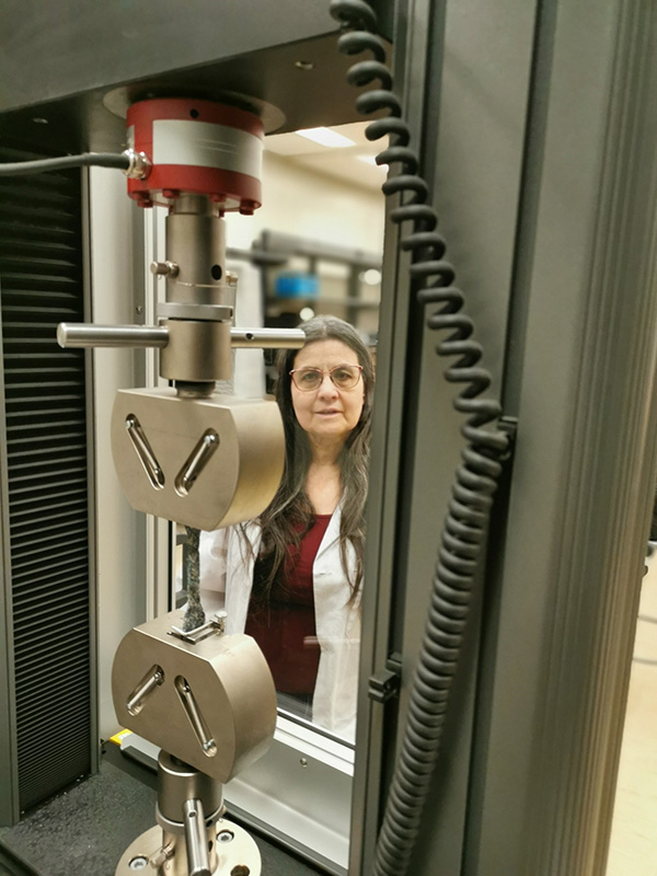 Dr. Denise Stilling looks on as a composite material made from discarded medical masks undergoes a tensile strength test.