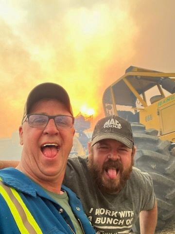 Tracy Wirstiuk and Clayton Clark pose for a selfie while the forest burns behind them. Tracy and Clayton along with James McRae, Braden Bura and Mike Bustin brought in equipment such as fire skidders to fight the Alberta wildfires just south of Entwistle.