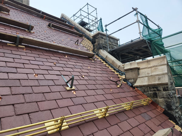 Replacement slate roofing with copper flashing and bronze snow guards in progress. Work is by Heather and Little.