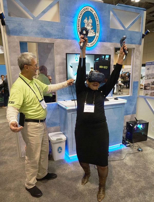 Joe Ciacchi, (green shirt), international representative of the Operative Plasterers’ and Cement Masons’ International Association of the U.S. and Canada, rewards delegate using virtual reality tools to plaster a virtual wall at the Buildings Show recently in Toronto.