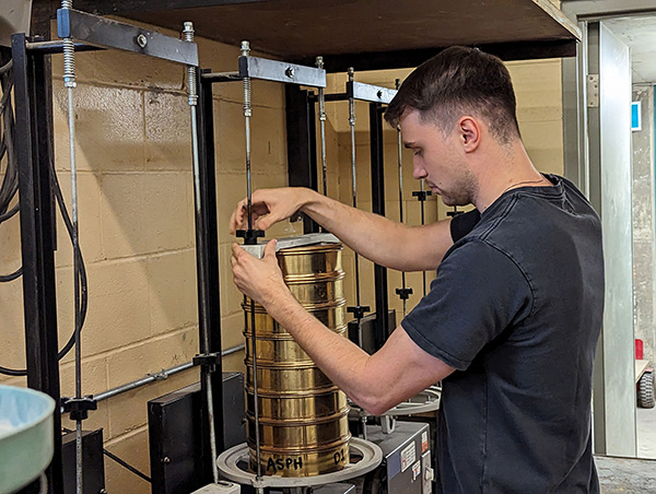 Civil Technology student Tyler Theim using a mechanical shaker to shake a sample through a sieve stack.