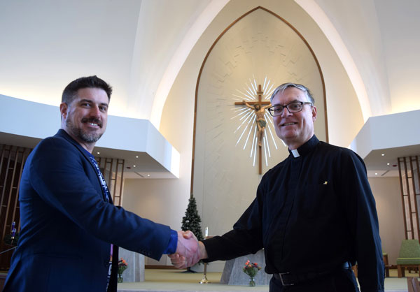 Father Mark Gatto, first pastor of St. Catherine of Siena, greets project manager Nolan Hunter of Hamilton’s Ira McDonald Construction.