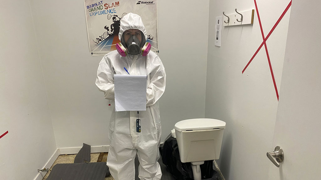 MacLeod is the first woman certified in asbestos removal in Canada. Shown is MacLeod assessing a situation. The marks on the wall indicate the amount of drywall to be removed. X means the entire wall goes and the straight line indicates all drywall below that line is coming down.