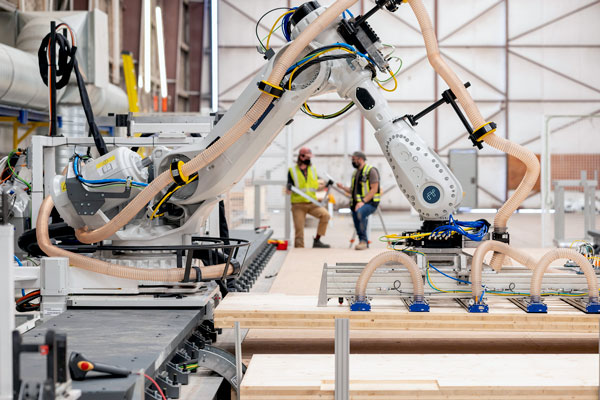 The factory has five big industrial robots arranged in manufacturing assembly zones that together comprise a safe assembly line. The robots, which are remote-controlled with proprietary software, lift, position and custom-cut panels of mass-timber walls, floors and ceilings.