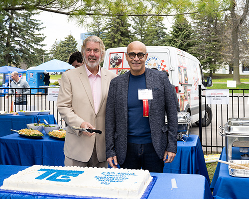 John Mollenhauer, president of the Toronto Construction Association and Ed Applebaum, principal Montgomery Sisam Architects (retired) and chair of the TCA board of directors cut the cake during the barbecue.