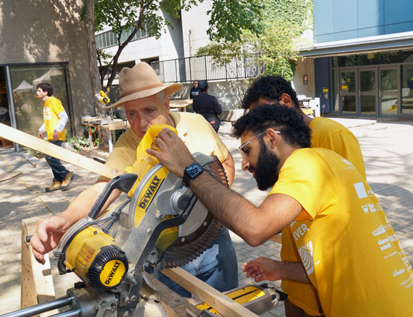 Carpenter Maarten Bomers gives advice on cuts to TimberFever participants Fayaz Adam and Sathya Reddy.