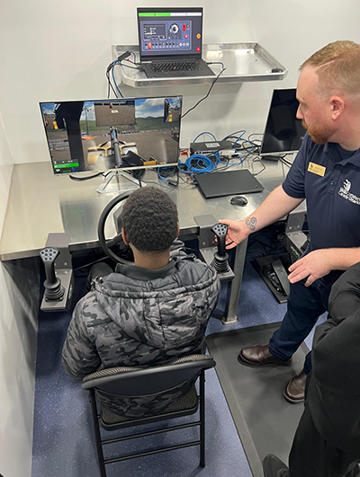 A Skills Ontario staff member and student use the heavy equipment simulator together at the Mississauga Level Up! Career Fair.