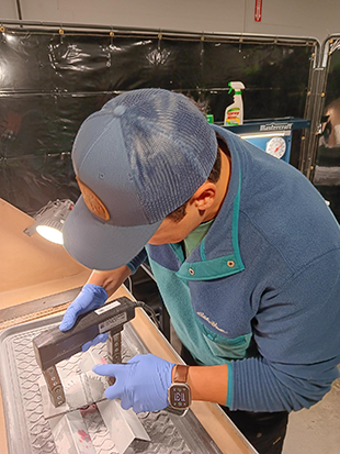 Ethan Martin applying magnetic particles to a test specimen with a magnetic yoke.