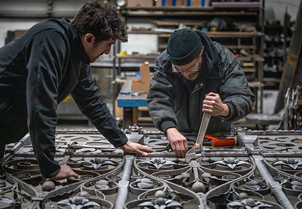Two heritage metal restoration professionals reassemble a gate in Dominion Restoration’s workshop.